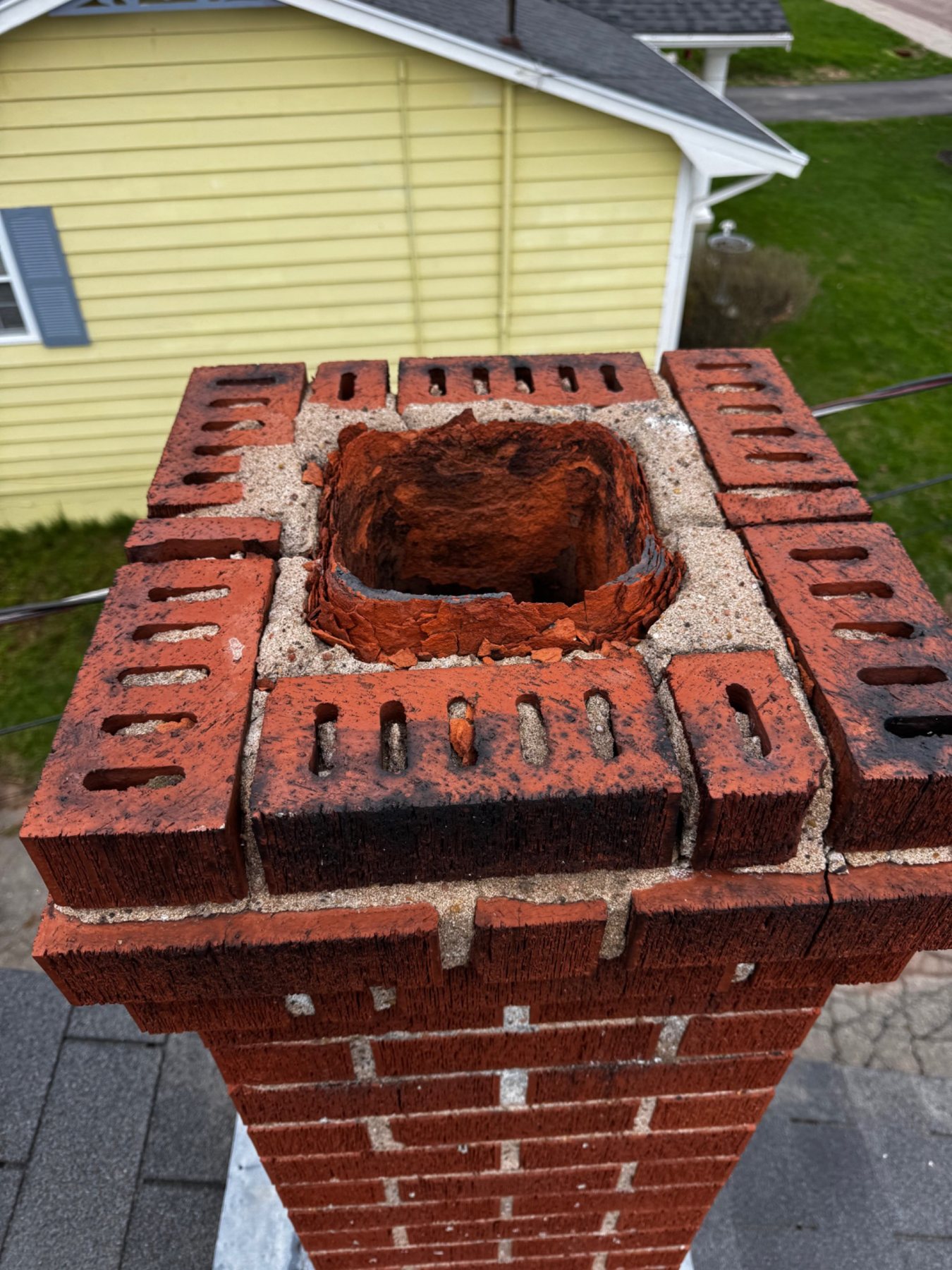 Deteriorated clay flue liner visible at the top of a masonry chimney