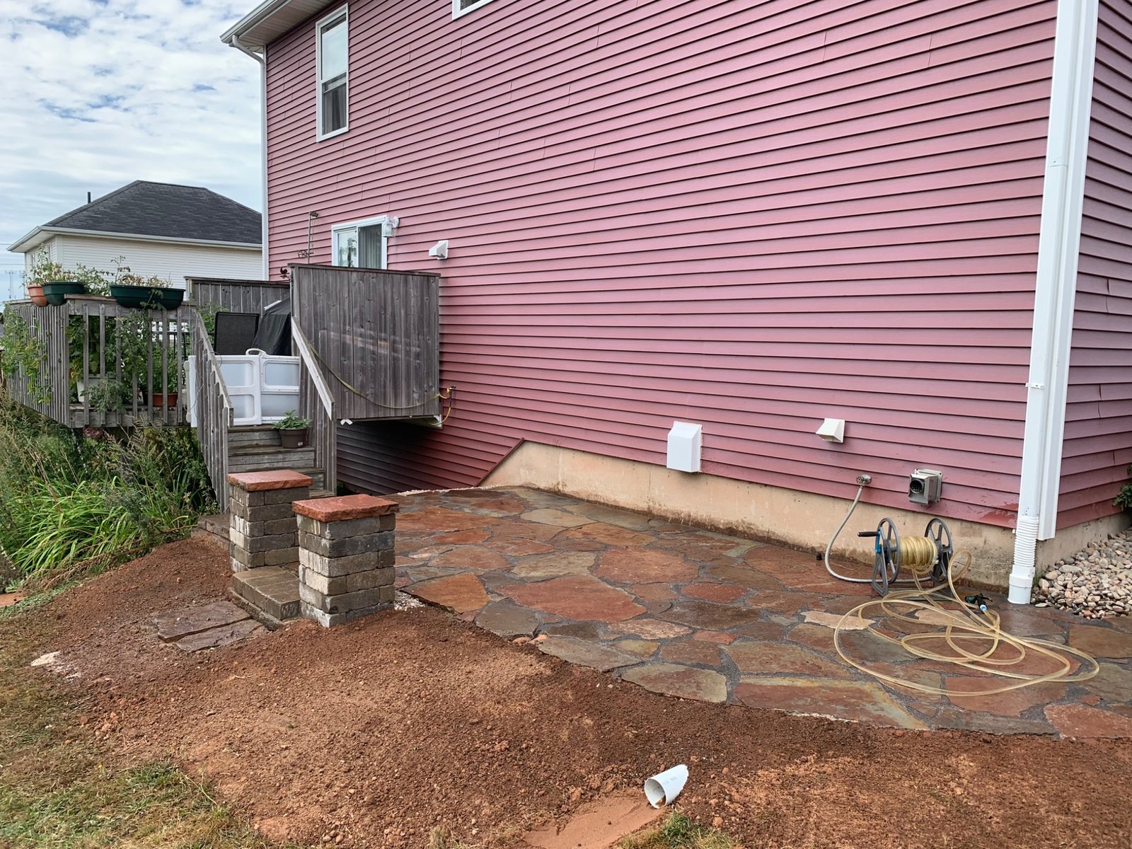 Flagstone patio and walkway installed with drainage and grading improvements beside a house