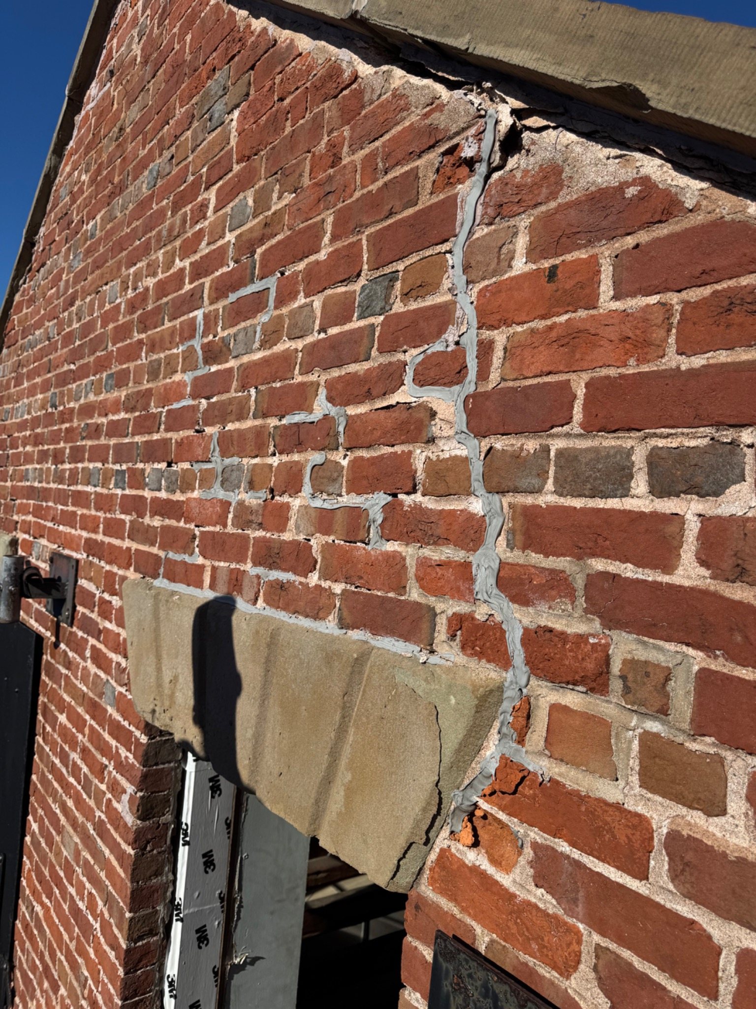 Historic brick wall with visible previous patching, cracking and older mortar