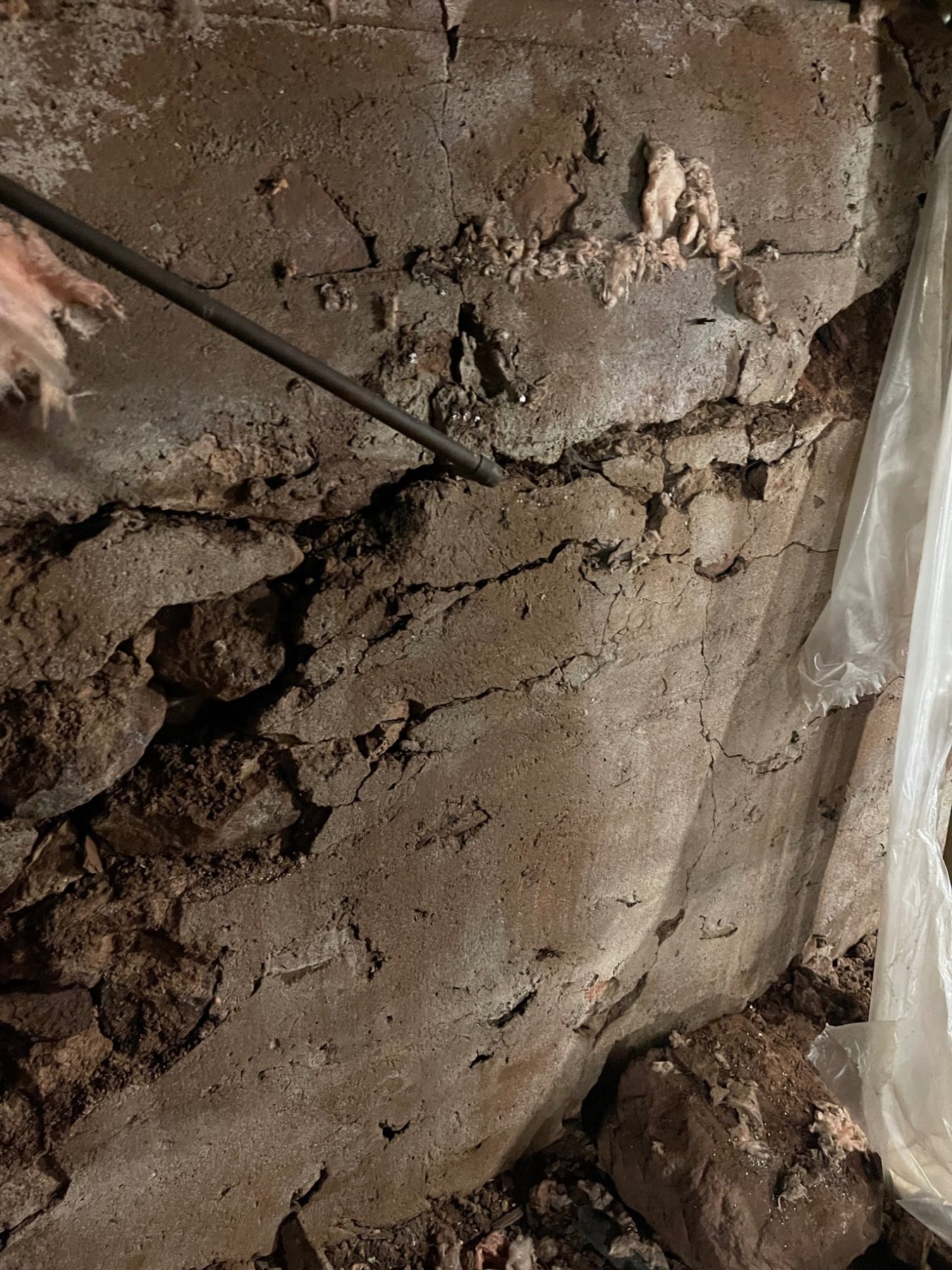 Parged stone foundation showing a cementitious surface coat over older masonry